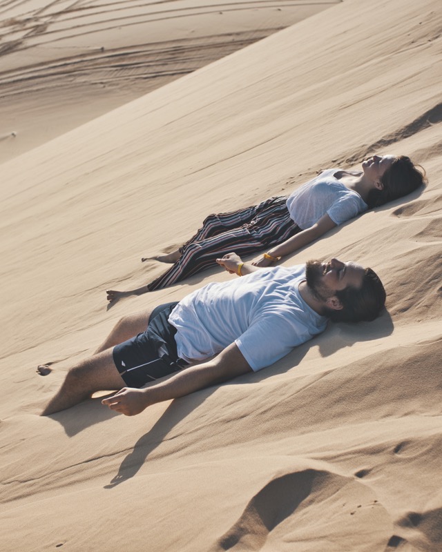 Young couple laying in white sand dunes, Mui Ne Vietnam