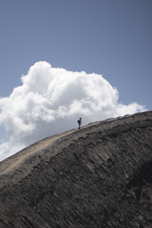 Person standing on edge of Mount Bromo, Java, on sunny day